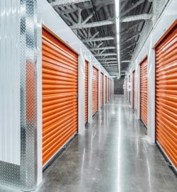 storage facility hallway showing a row of indoor self-storage units with orange doors
