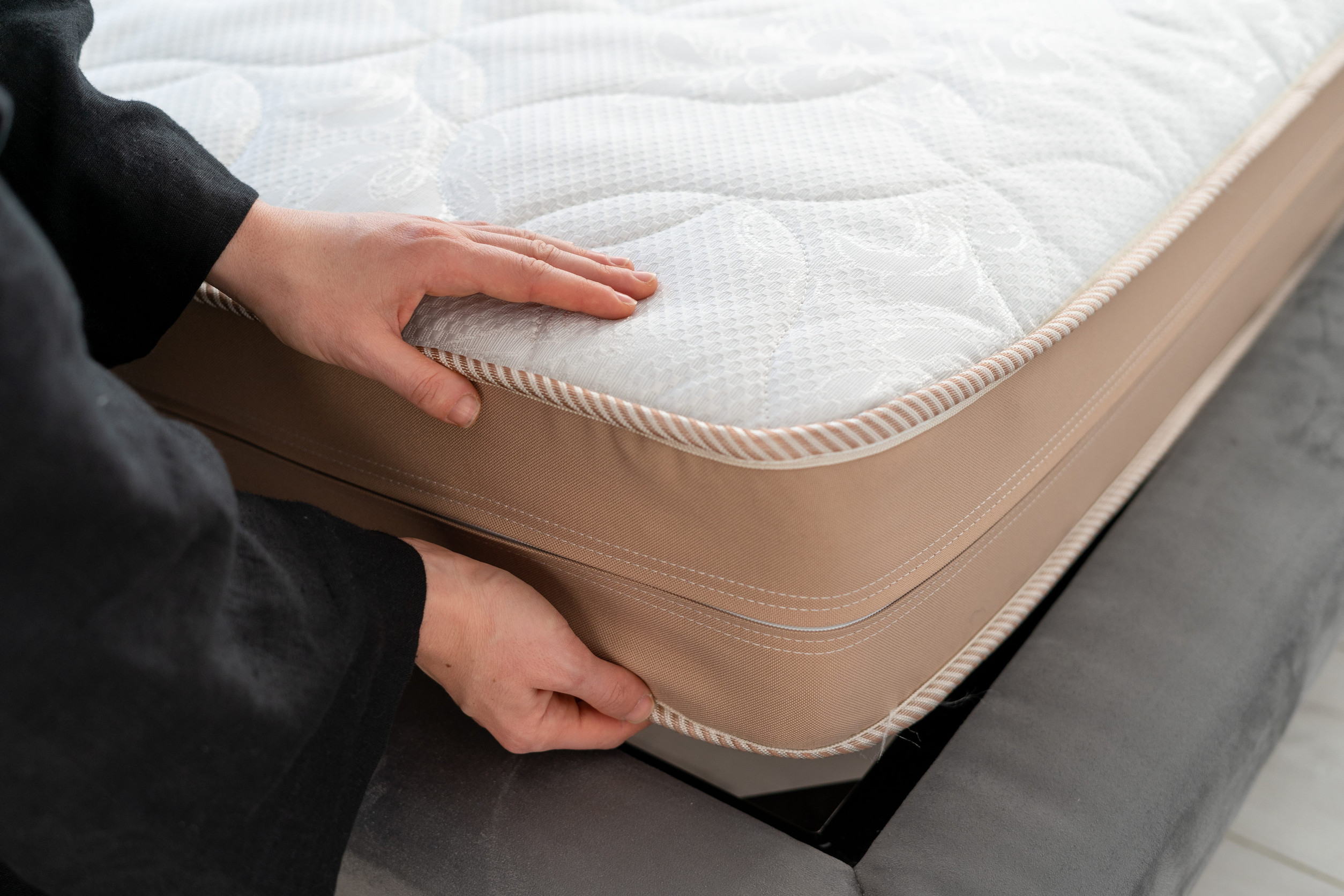 Person checking mattress seams for signs of bedbugs before storage.