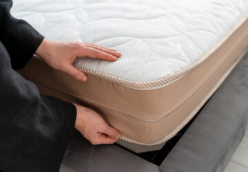 Personne vérifiant les coutures d’un matelas pour détecter des signes de punaises de lit avant l’entreposage.